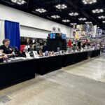 Author Val Willis at the Writers' Row Booth at Indy Pop Con 2023 surrounded by books.